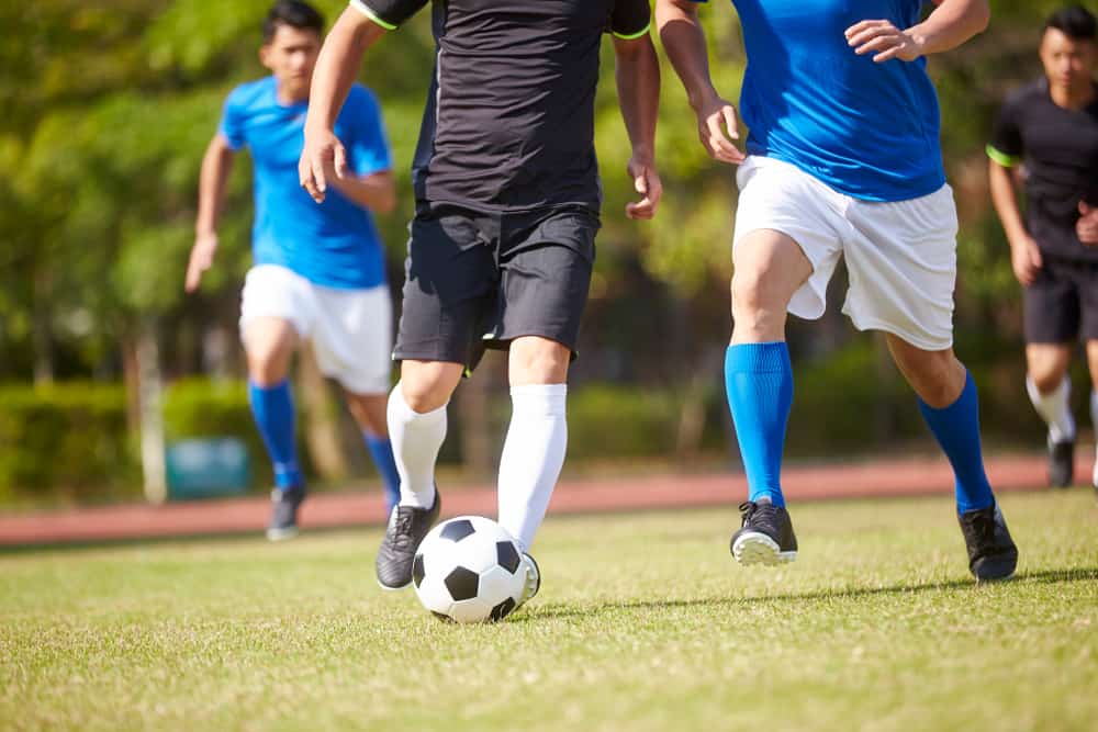 men playing soccer kicking soccer ball sports injuries